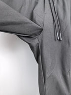 Dark fabric cargo pants detail with drape at knee and drawstring cords.