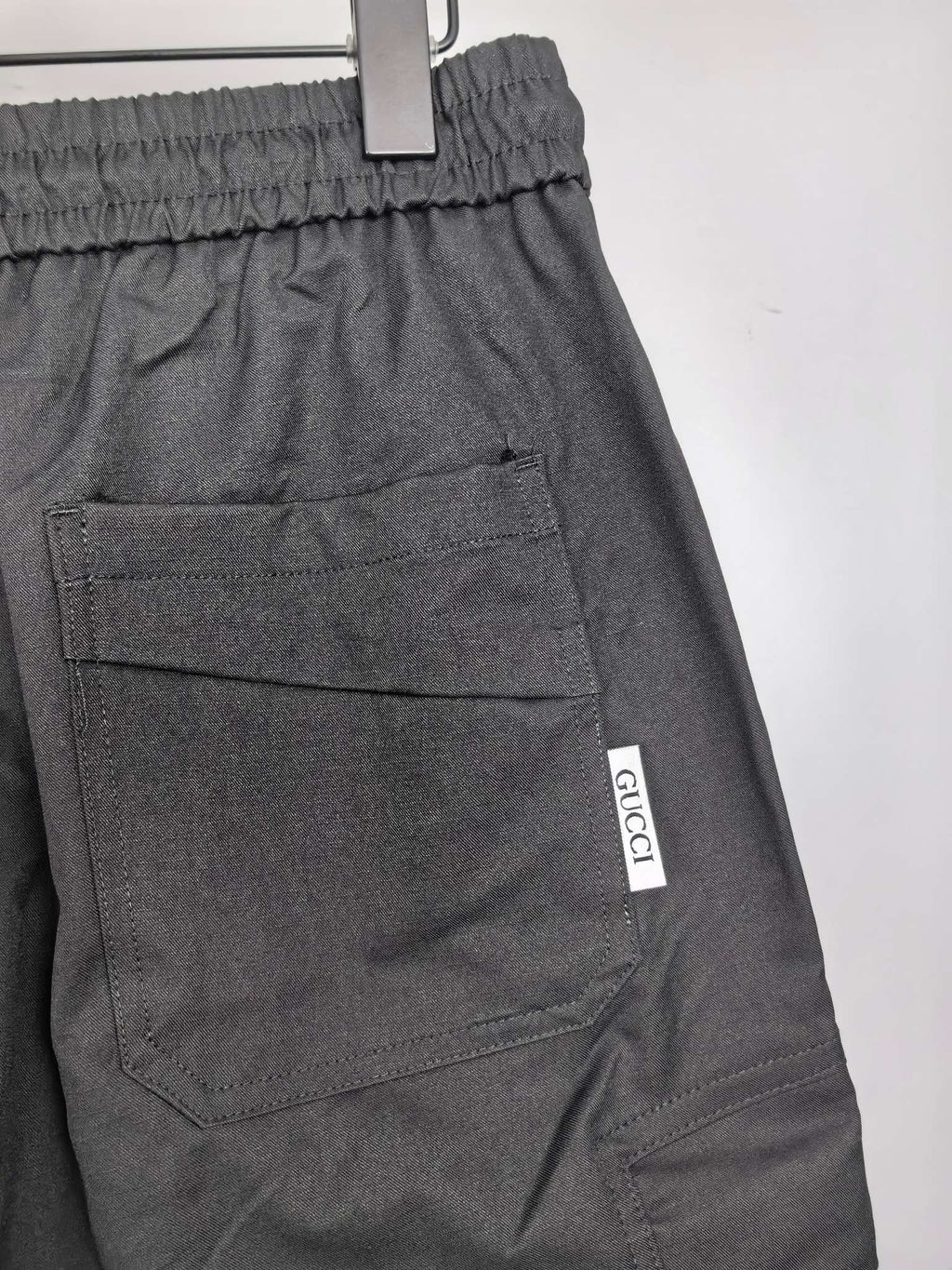 Dark cargo pants with elastic waistband, front pockets, and small GUCCI label.