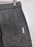 Dark cargo pants with elastic waistband, front pockets, and small GUCCI label.