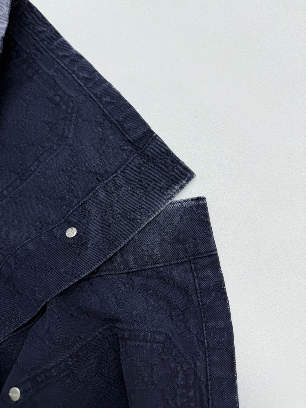 Gucci denim jacket sleeve and shoulder seam with snap buttons on dark navy