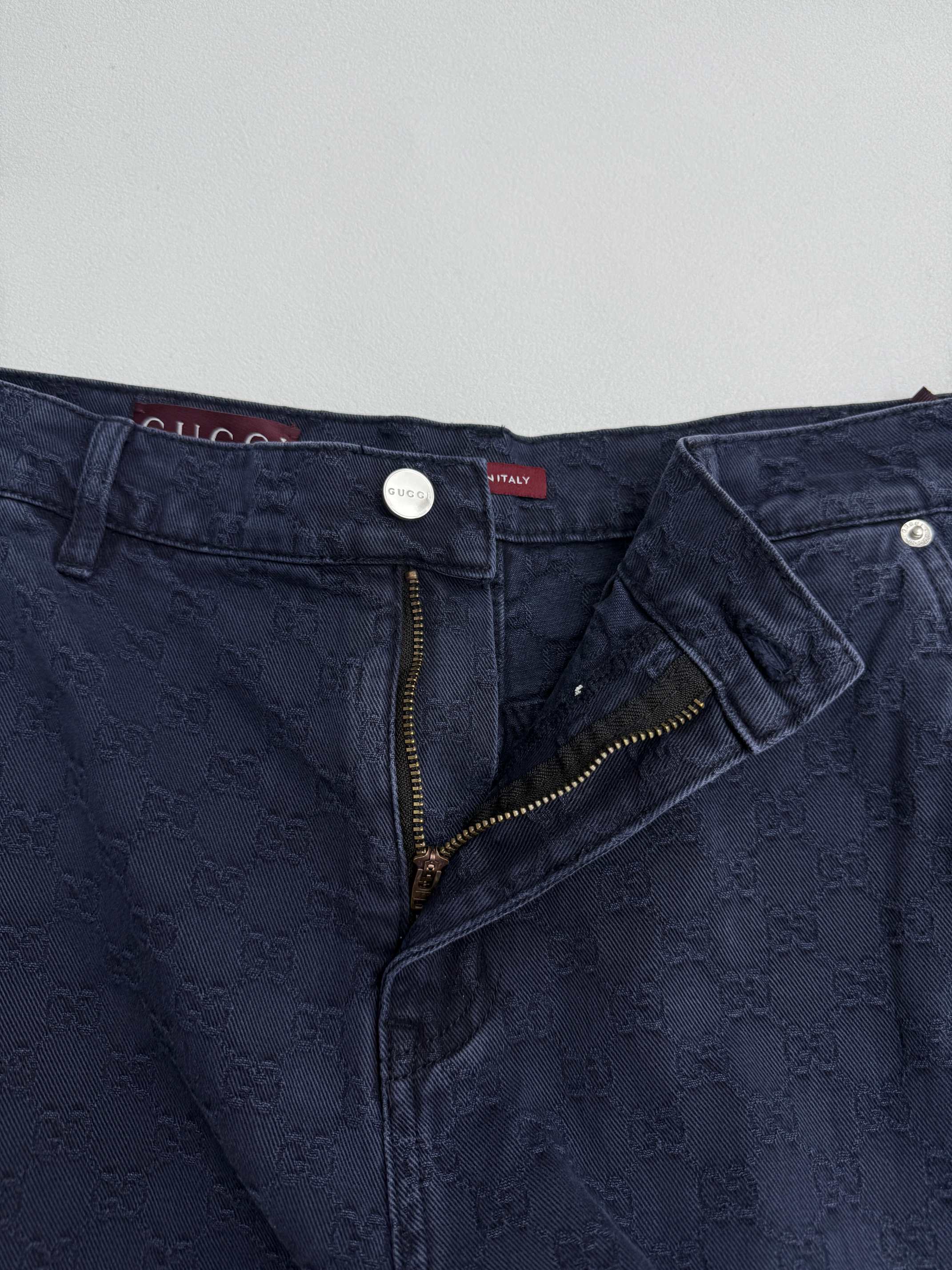 Navy Gucci pants waistband close-up, front zip fly and GG logo fabric pattern