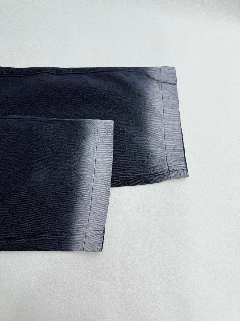 Navy Gucci pants hem close-up, side seam and cuff finish on GG-pattern fabric