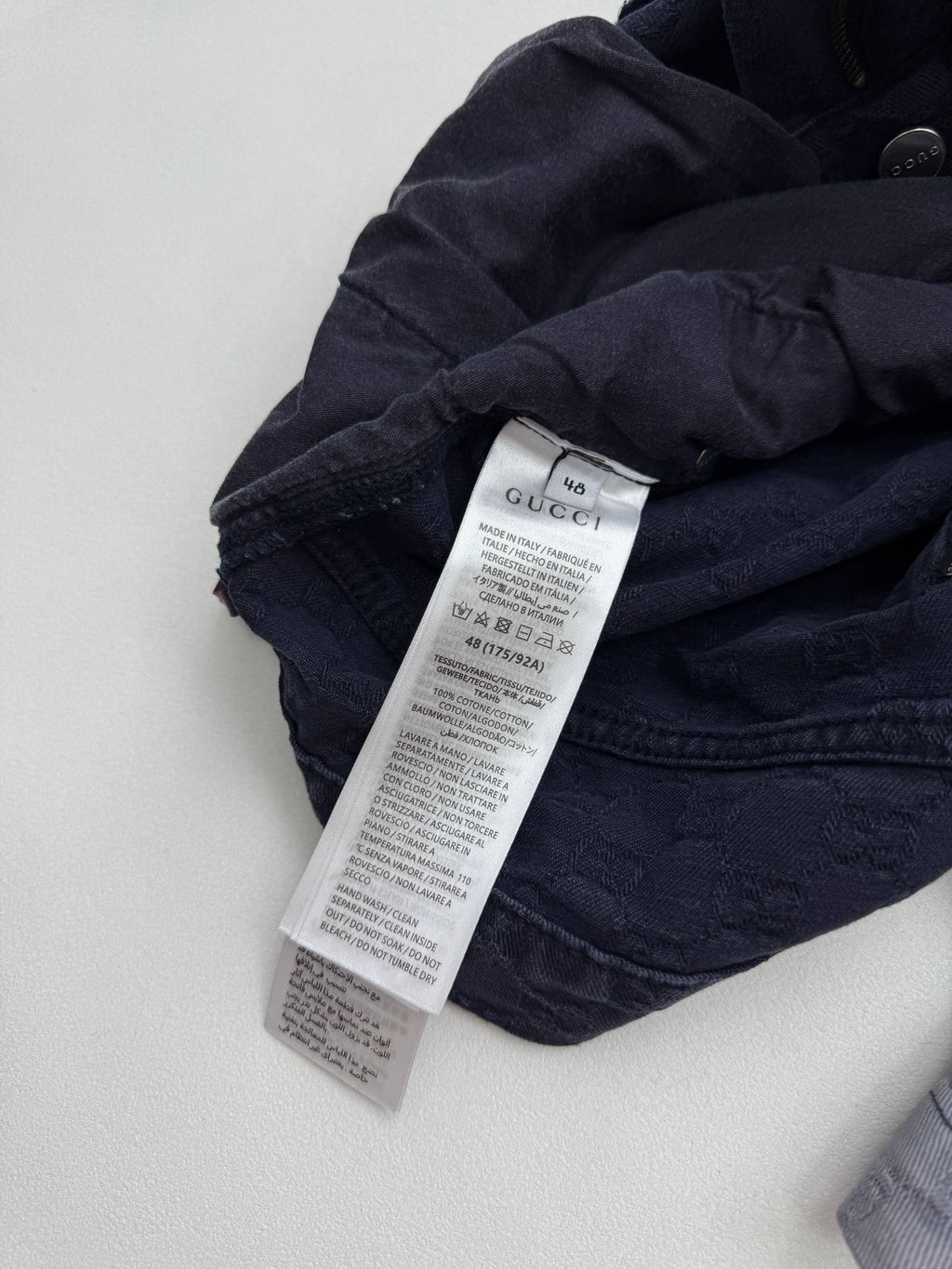 Gucci pants care label on dark GG-patterned fabric, folded waistband area