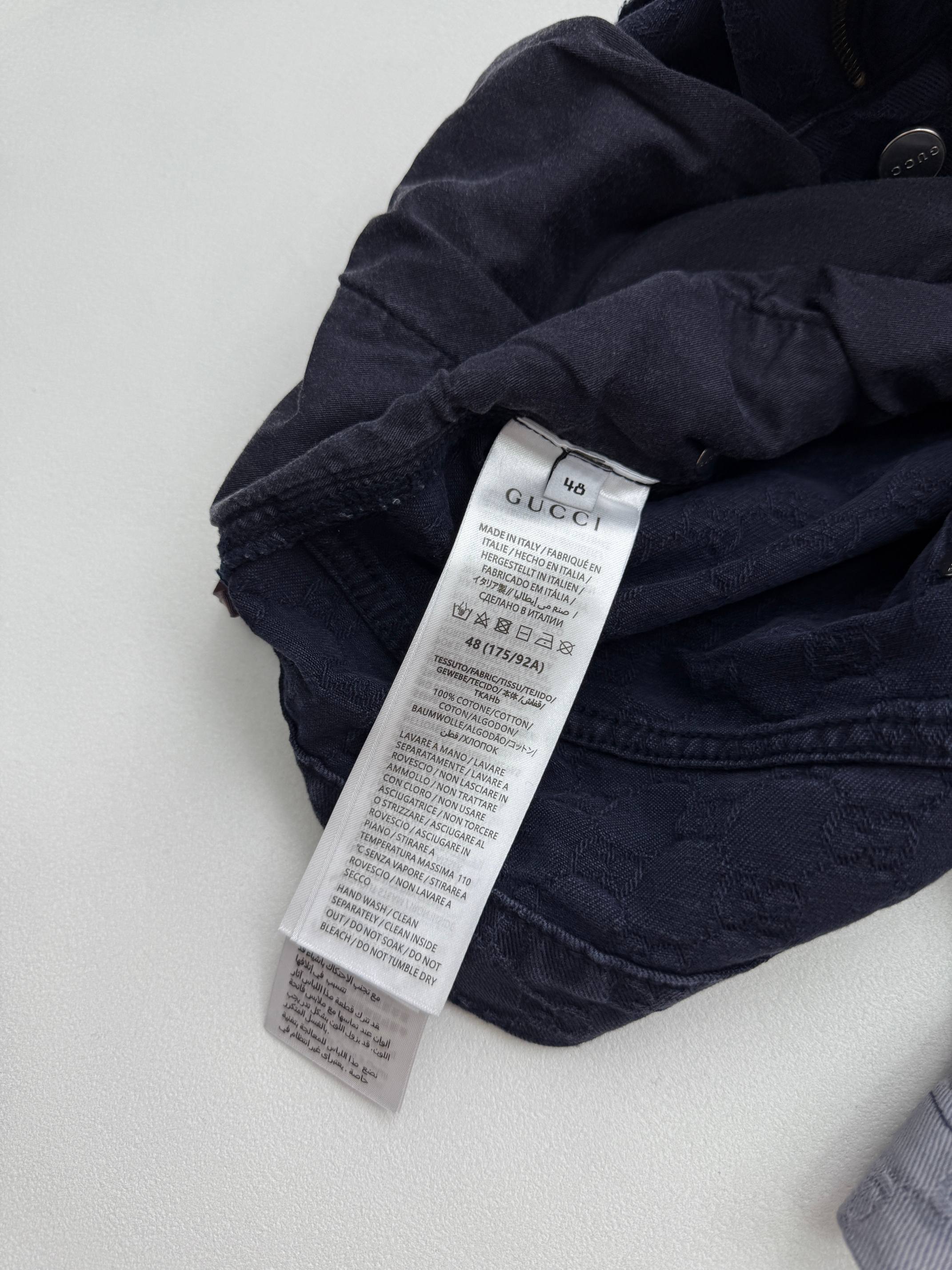 Gucci pants care label on dark GG-patterned fabric, folded waistband area