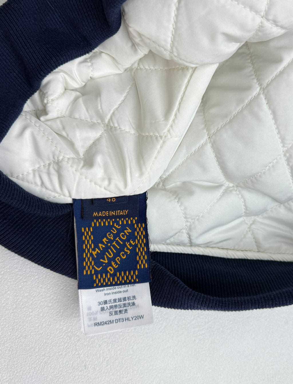 Louis Vuitton garment label on navy ribbed hem with care and size text