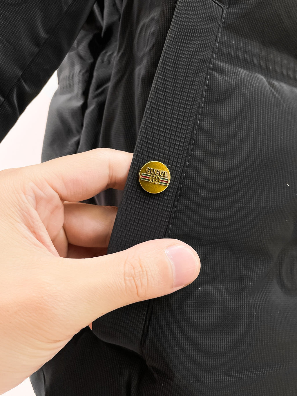 Long puffer jacket sleeve cuff with small round logo patch