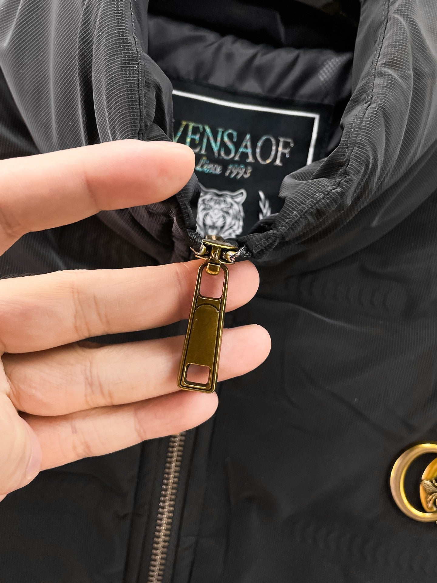Long puffer jacket zipper pull with crest detail and leather tag