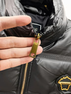 Black puffer jacket close-up of gold zipper pull and inner collar label