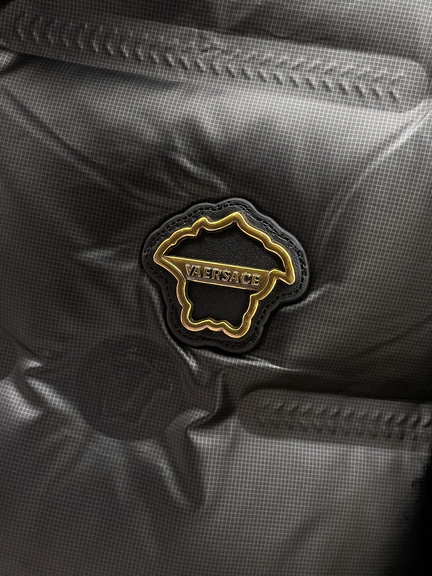 Black puffer jacket close-up of embroidered Versace logo patch
