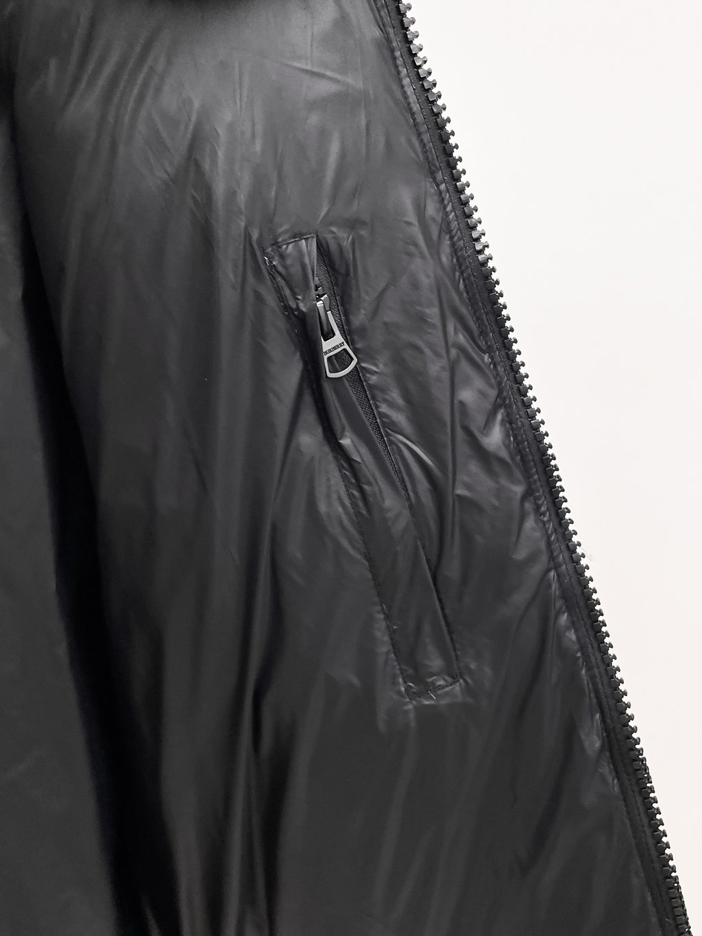 Burberry long puffer jacket, dark shiny black, close-up of side zipper and fabric quilting.