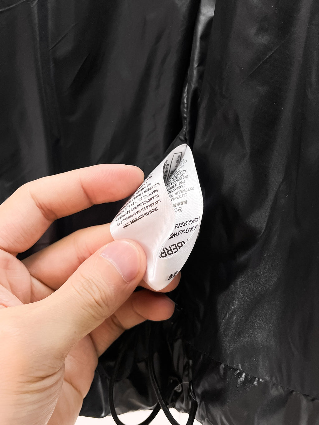 Black puffer jacket interior care label with size and fabric info