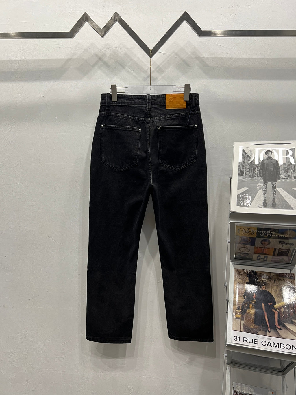 Black denim pants with metal button closure and five-pocket styling