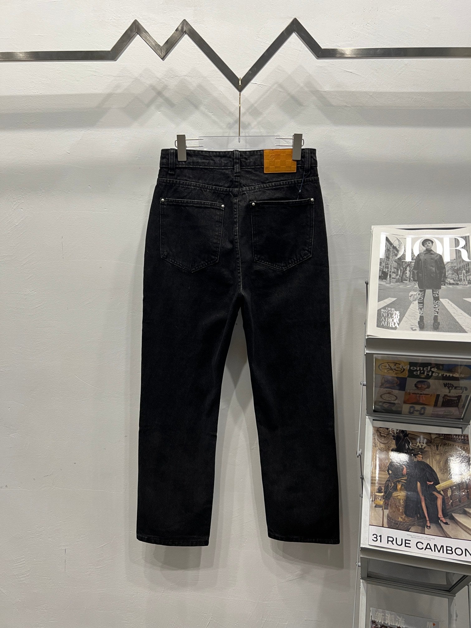 Black denim pants with metal button closure and five-pocket styling