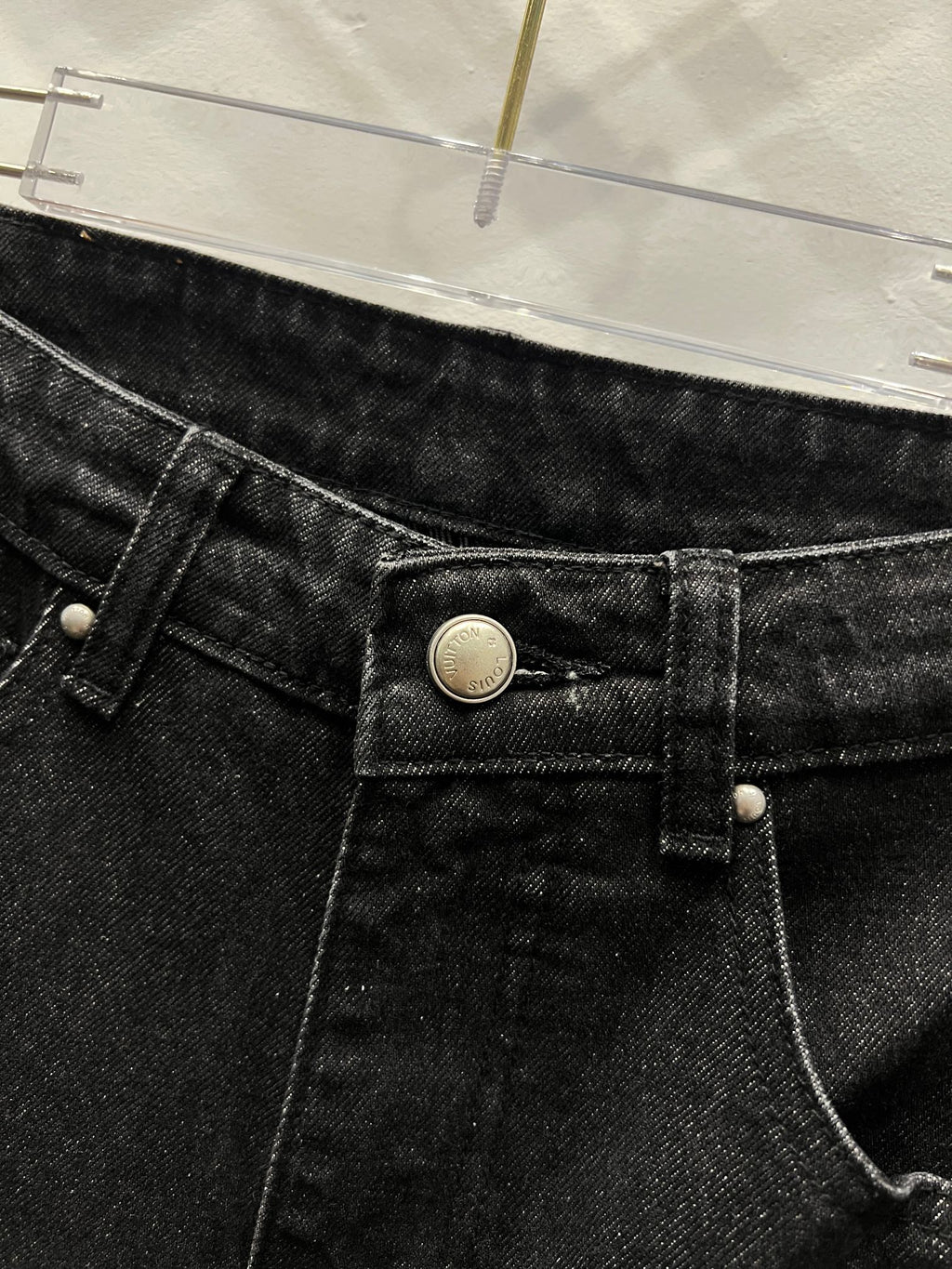 Black denim pants close-up of front button, waistband, and belt loops