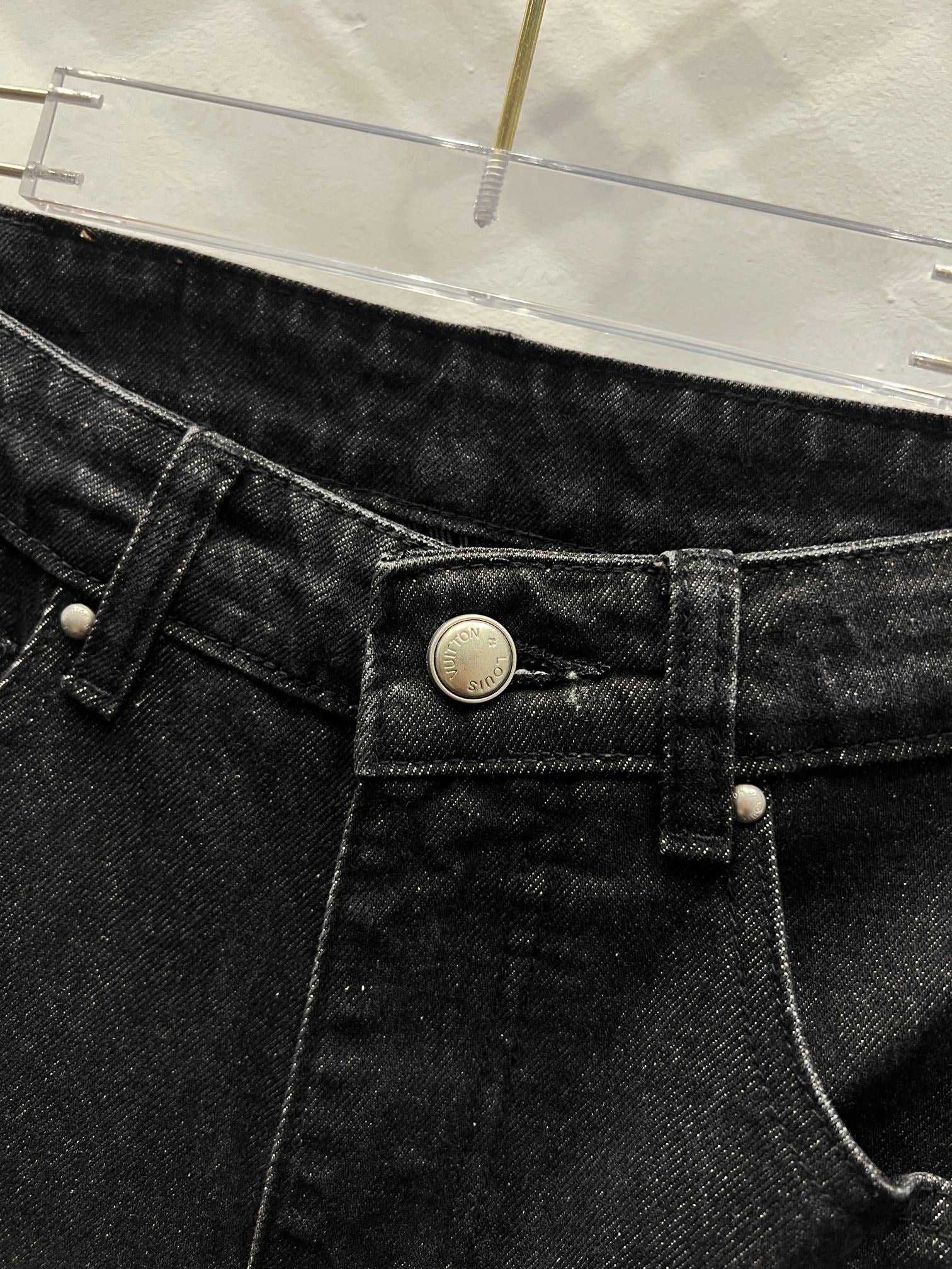 Black denim pants close-up of front button, waistband, and belt loops