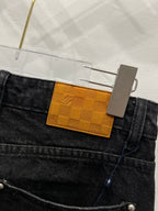 Black denim waistband detail with checkered orange LV logo tag