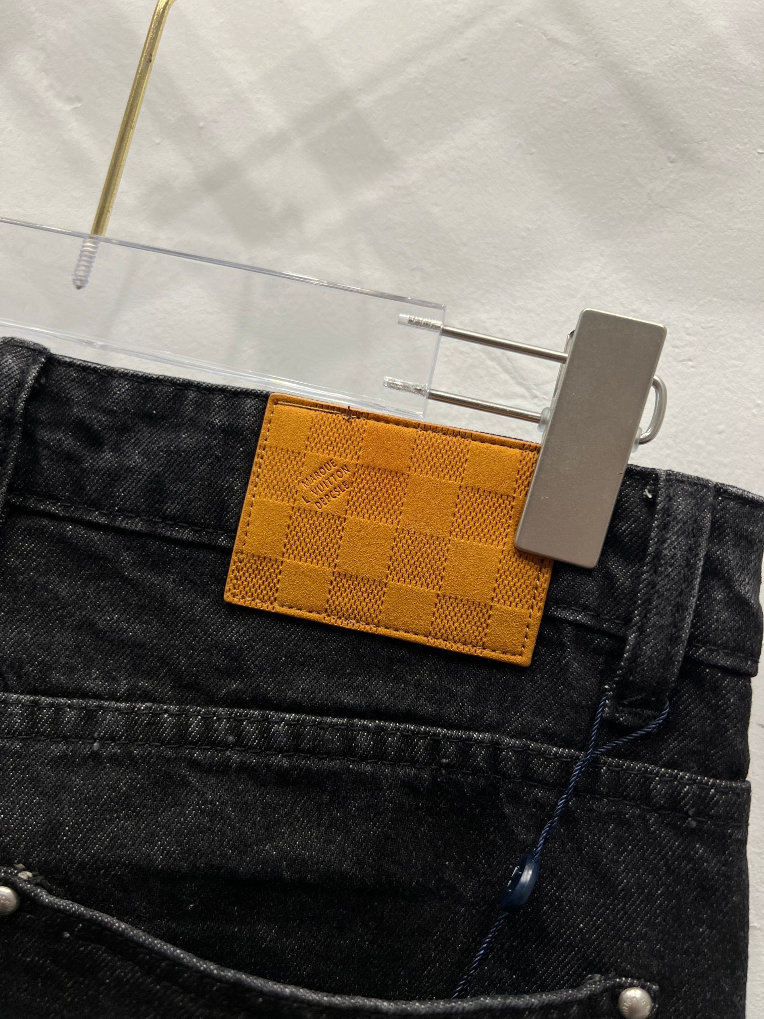 Black denim waistband detail with checkered orange LV logo tag