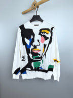 White long-sleeve crewneck sweater with multicolor abstract face graphic on front