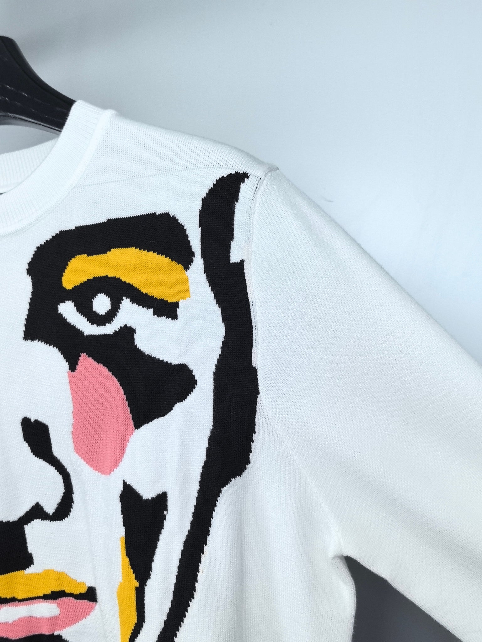 White long-sleeve sweater with multicolor face graphic detail on sleeve