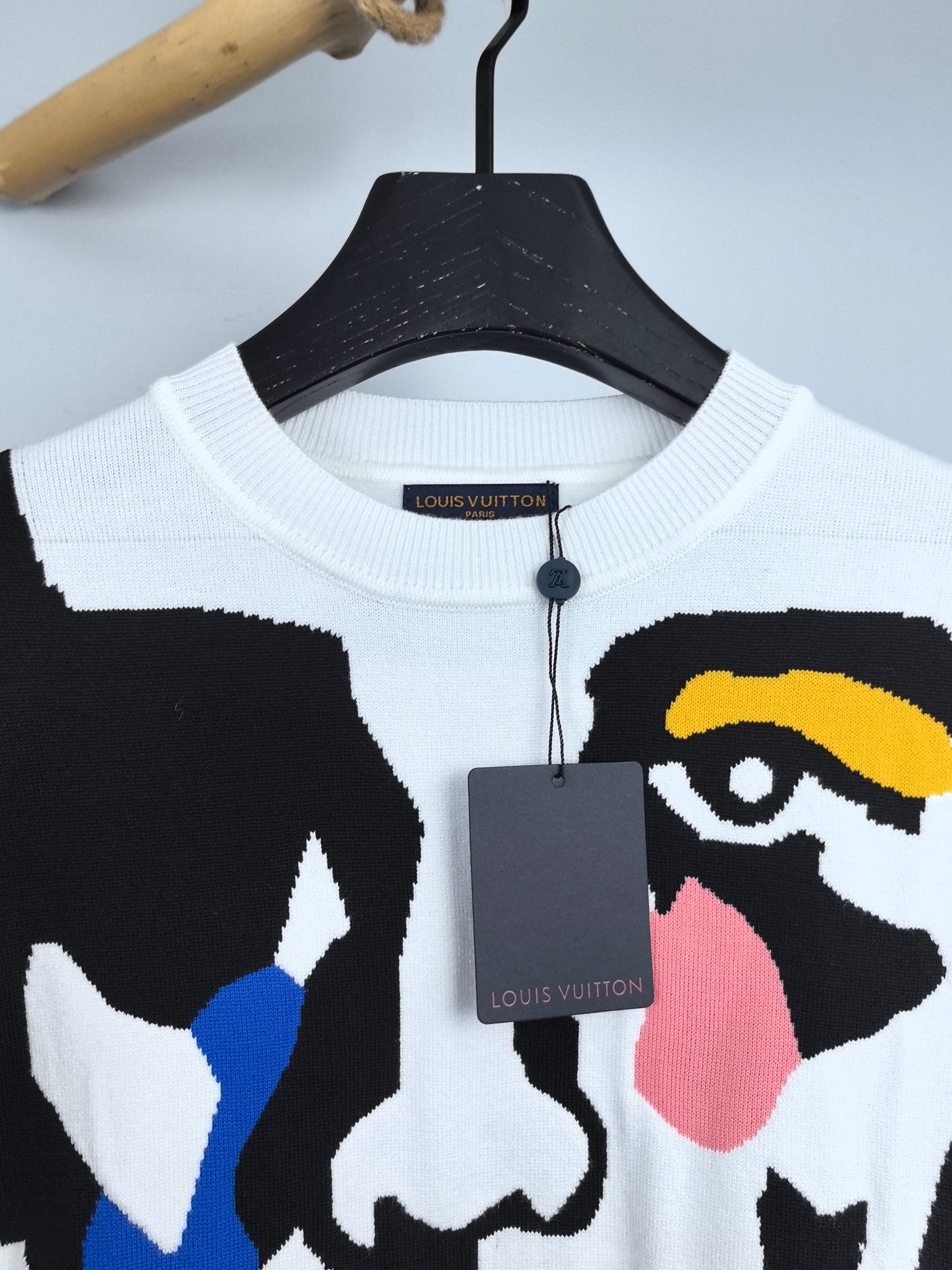 White crewneck sweater with Louis Vuitton neck label and partial multicolor face graphic