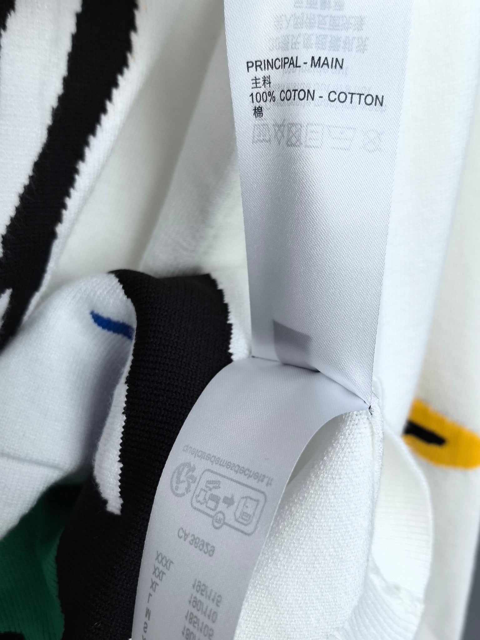 White sweater fabric with care and material label reading "COTTON" and symbols