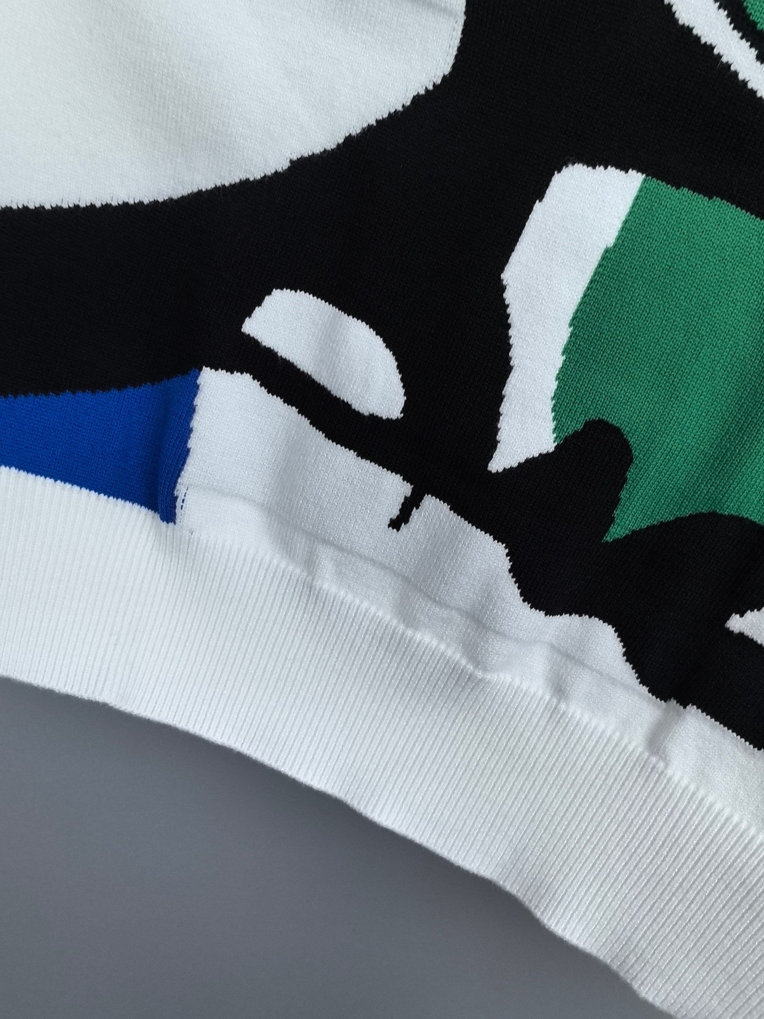 White sweater hem with multicolor graphic shapes and ribbed knit cuff