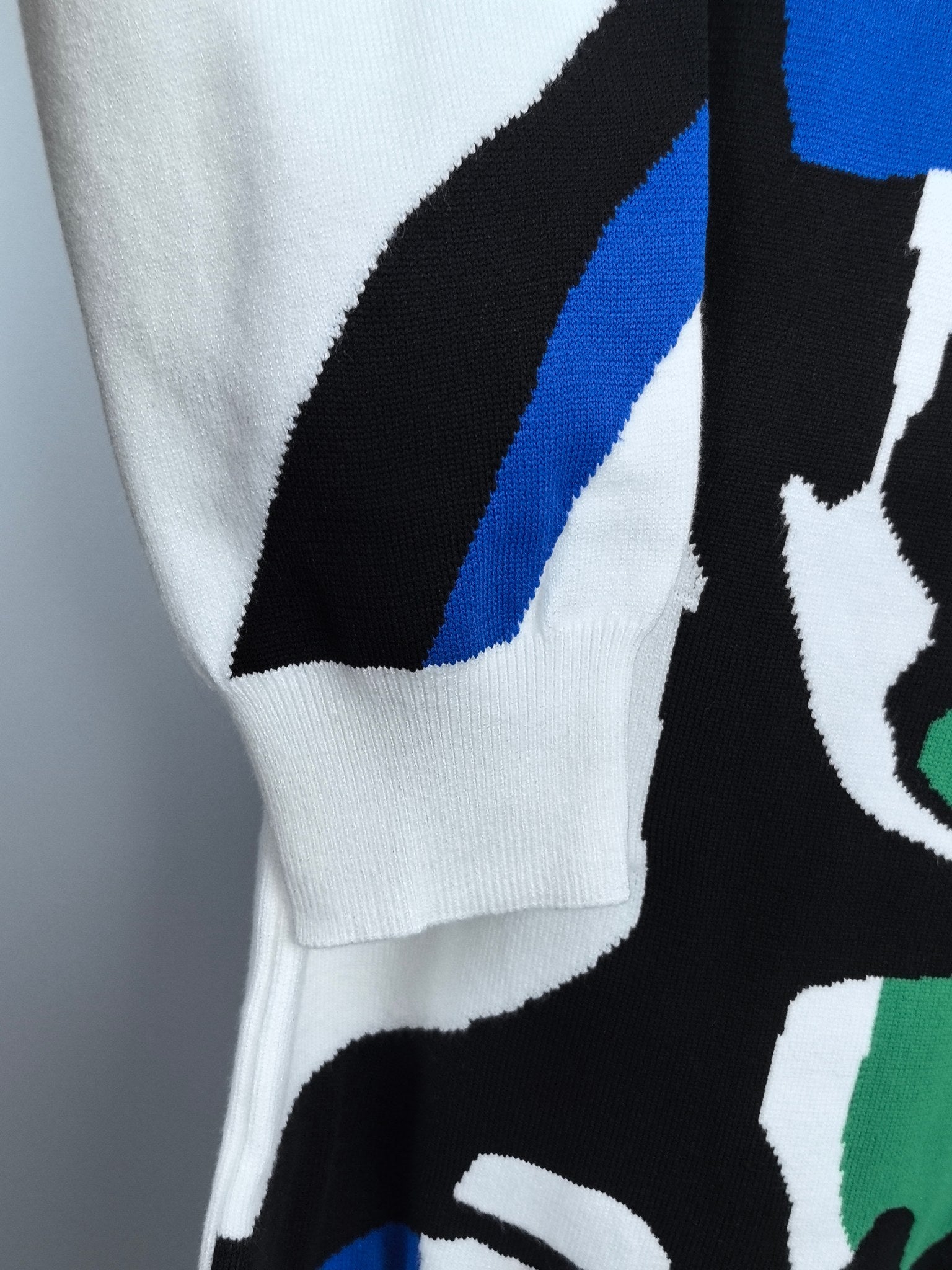 White long-sleeve sweater sleeve with black and blue graphic detail