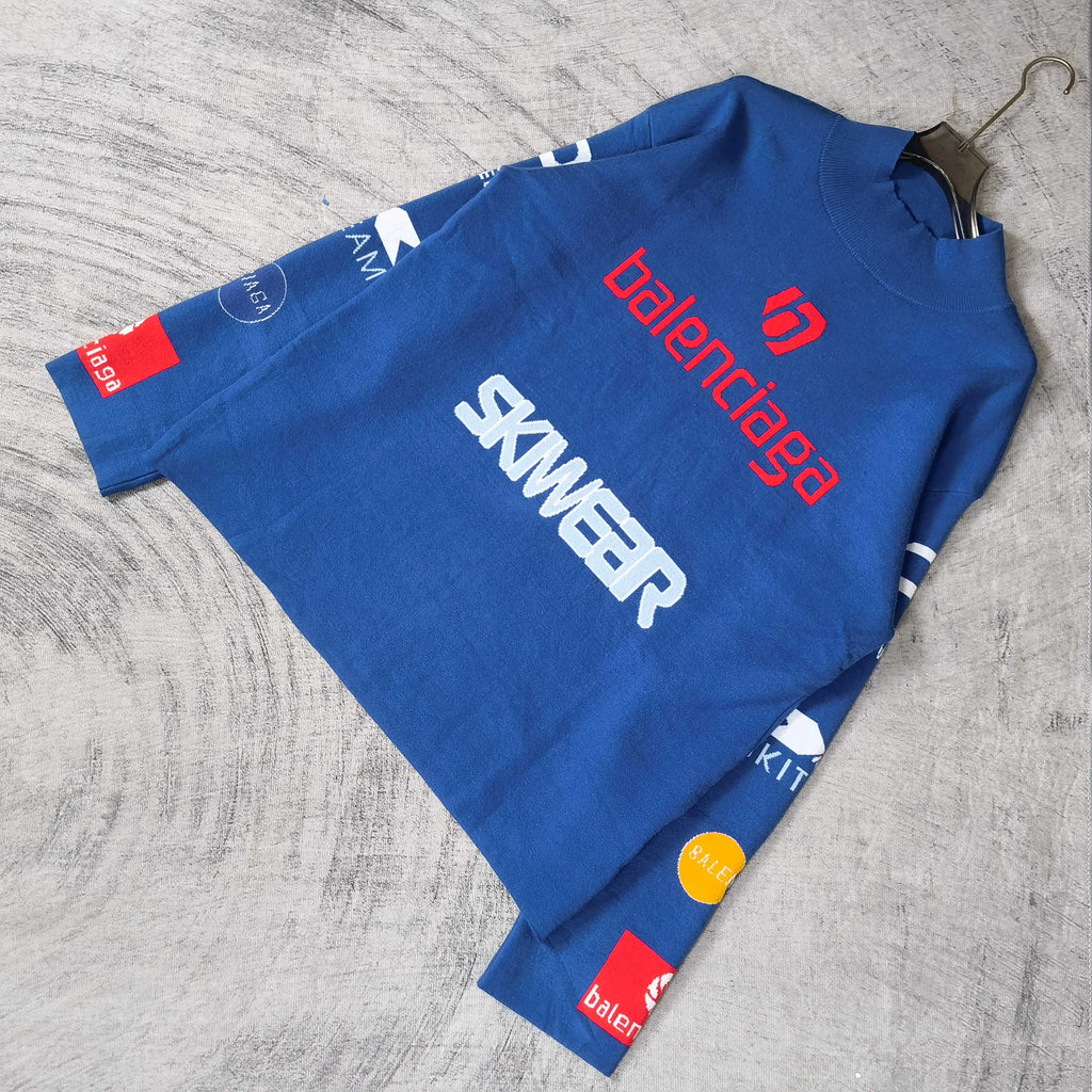 Blue long-sleeve sweater laid flat with SKWEAR graphic and red balenciaga logo