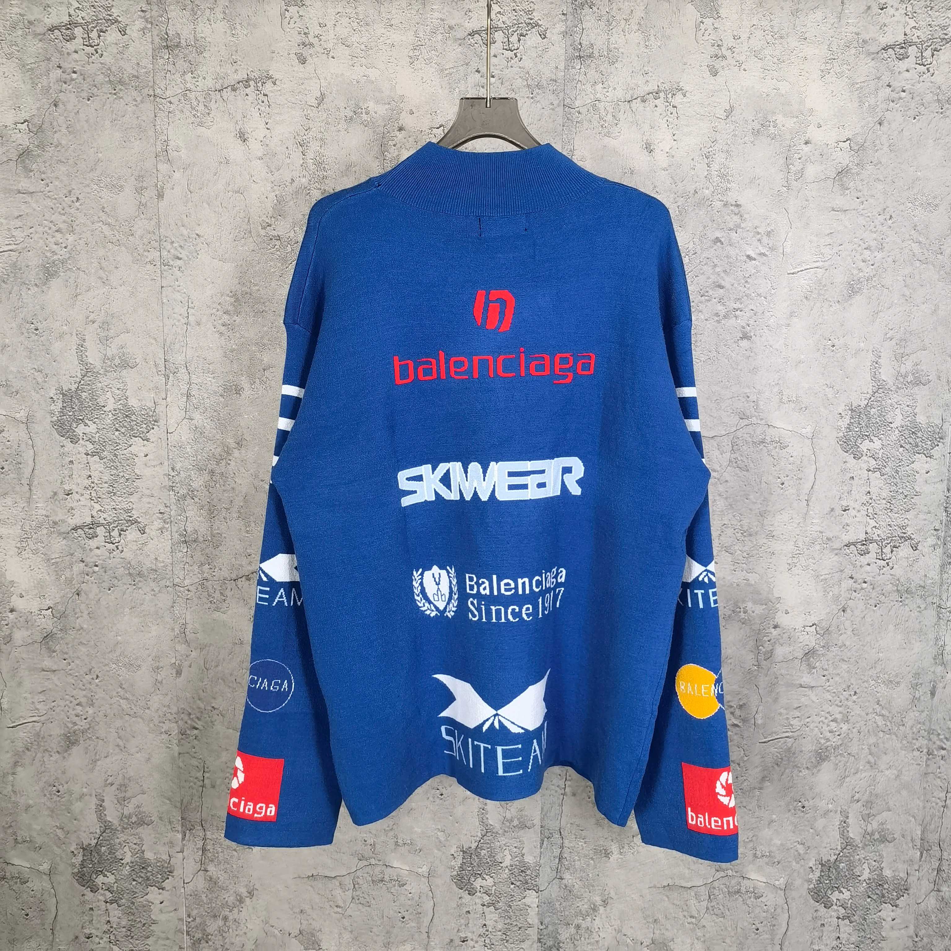 Blue long-sleeve sweater with back logo text and emblem patches