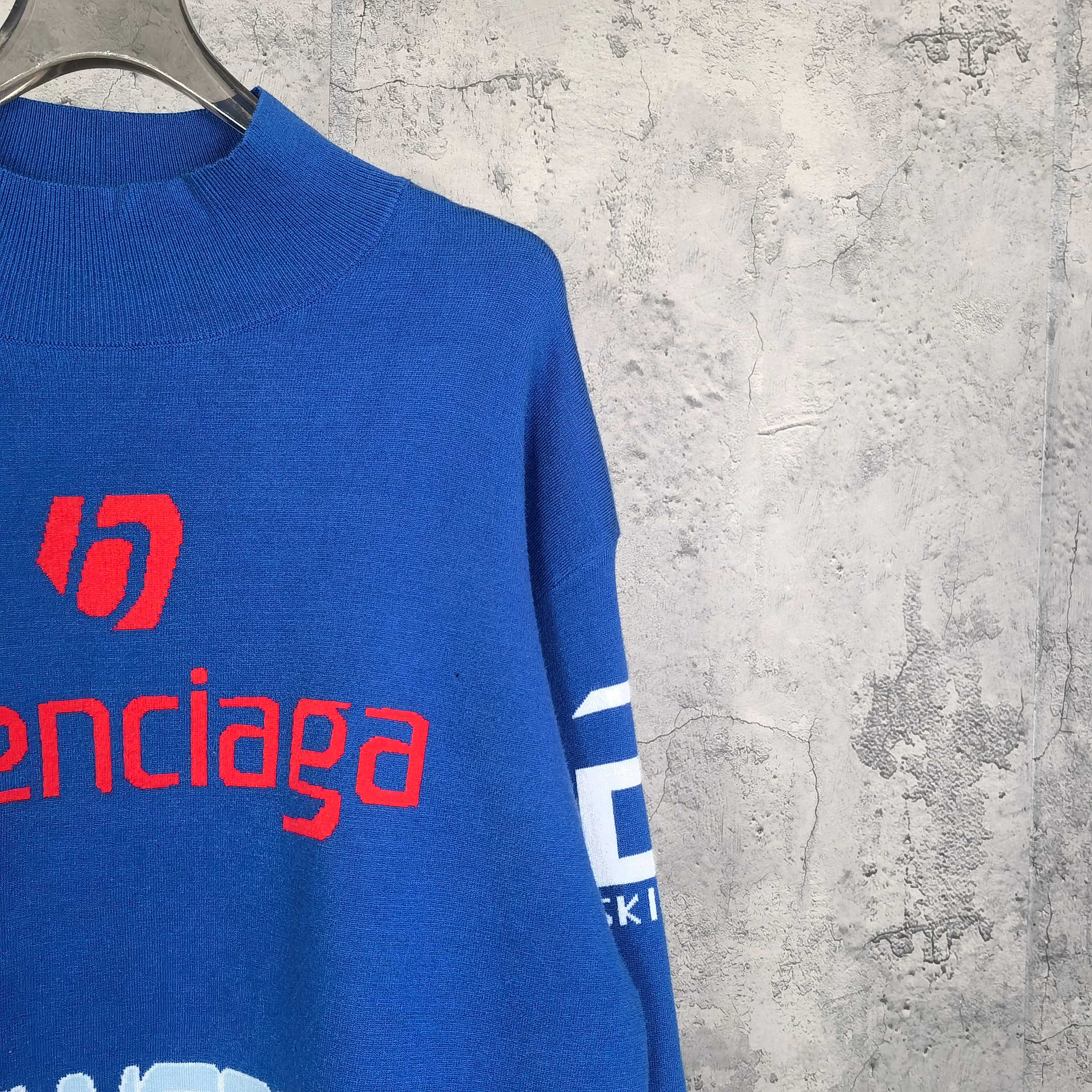 Blue sweater sleeve with white stripe cuff and red balenciaga logo print