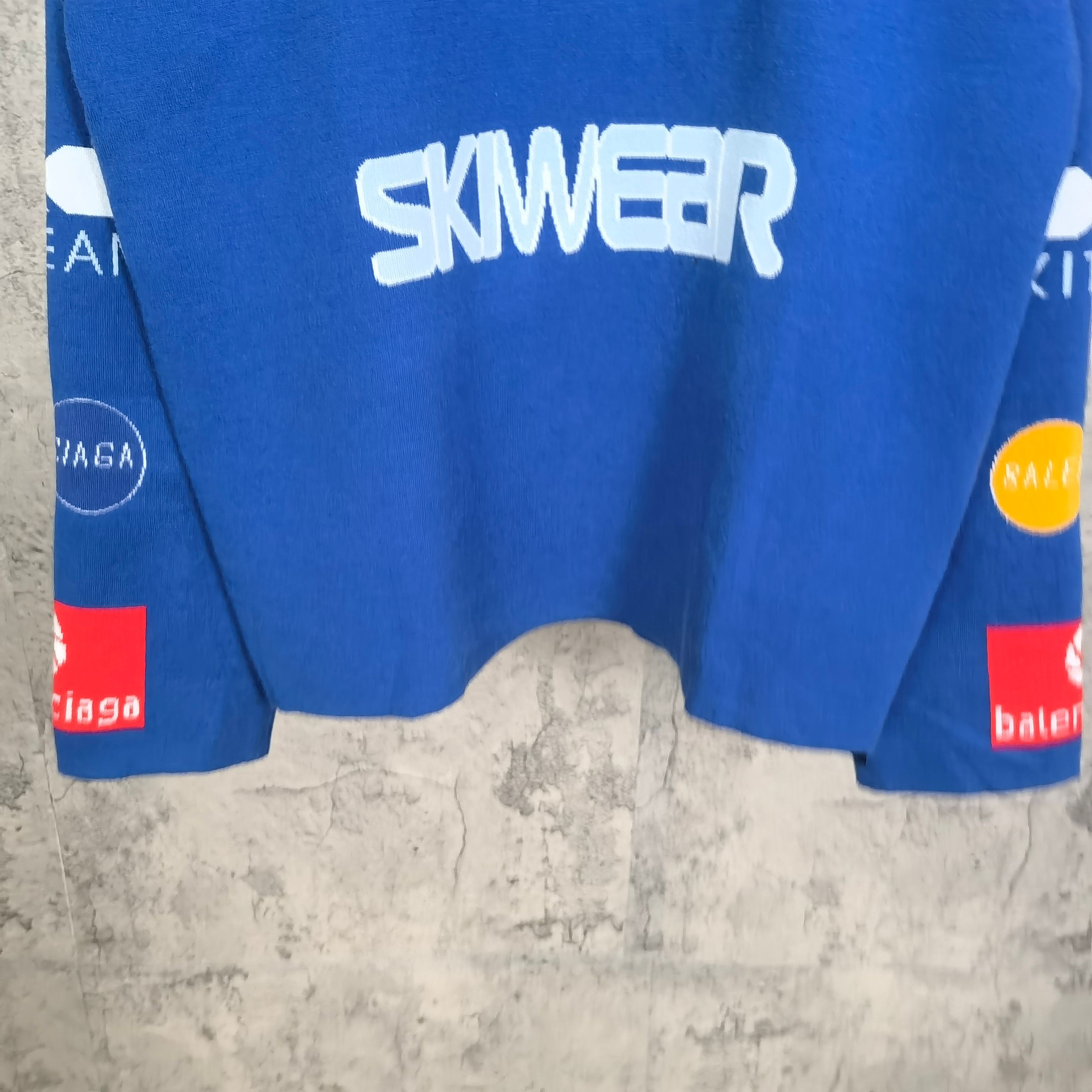 Blue long-sleeve shirt front hem with 'SKWER' logo and graphic sleeve prints