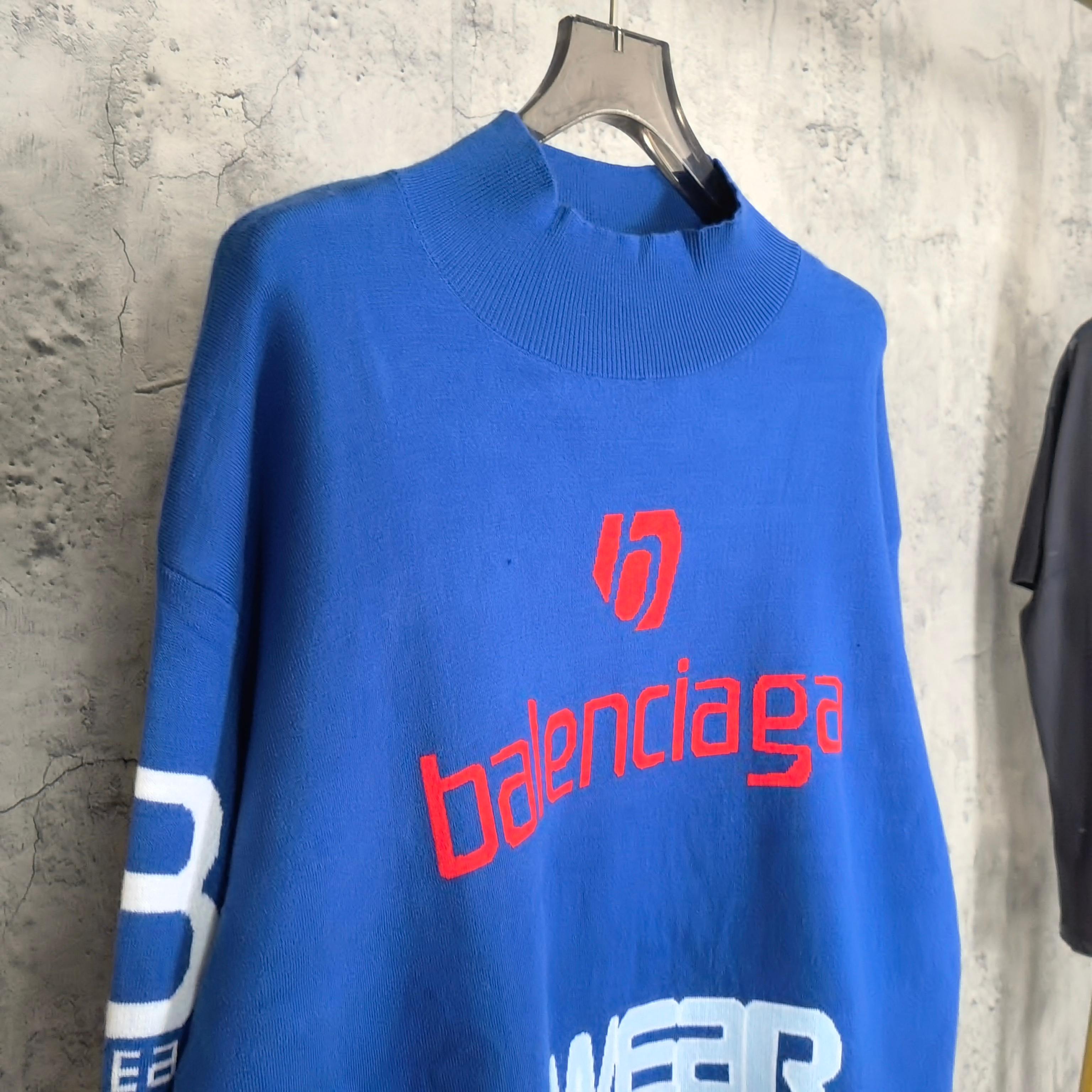 Blue sweater with red balenciaga logo and white SKWEAR graphic across chest