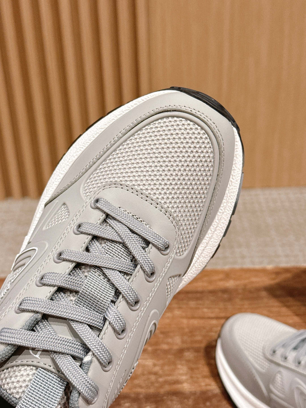 Light gray sneaker upper close-up with lace eyelets and textured fabric