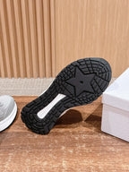 Black outsole of a light gray sneaker, showing tread pattern