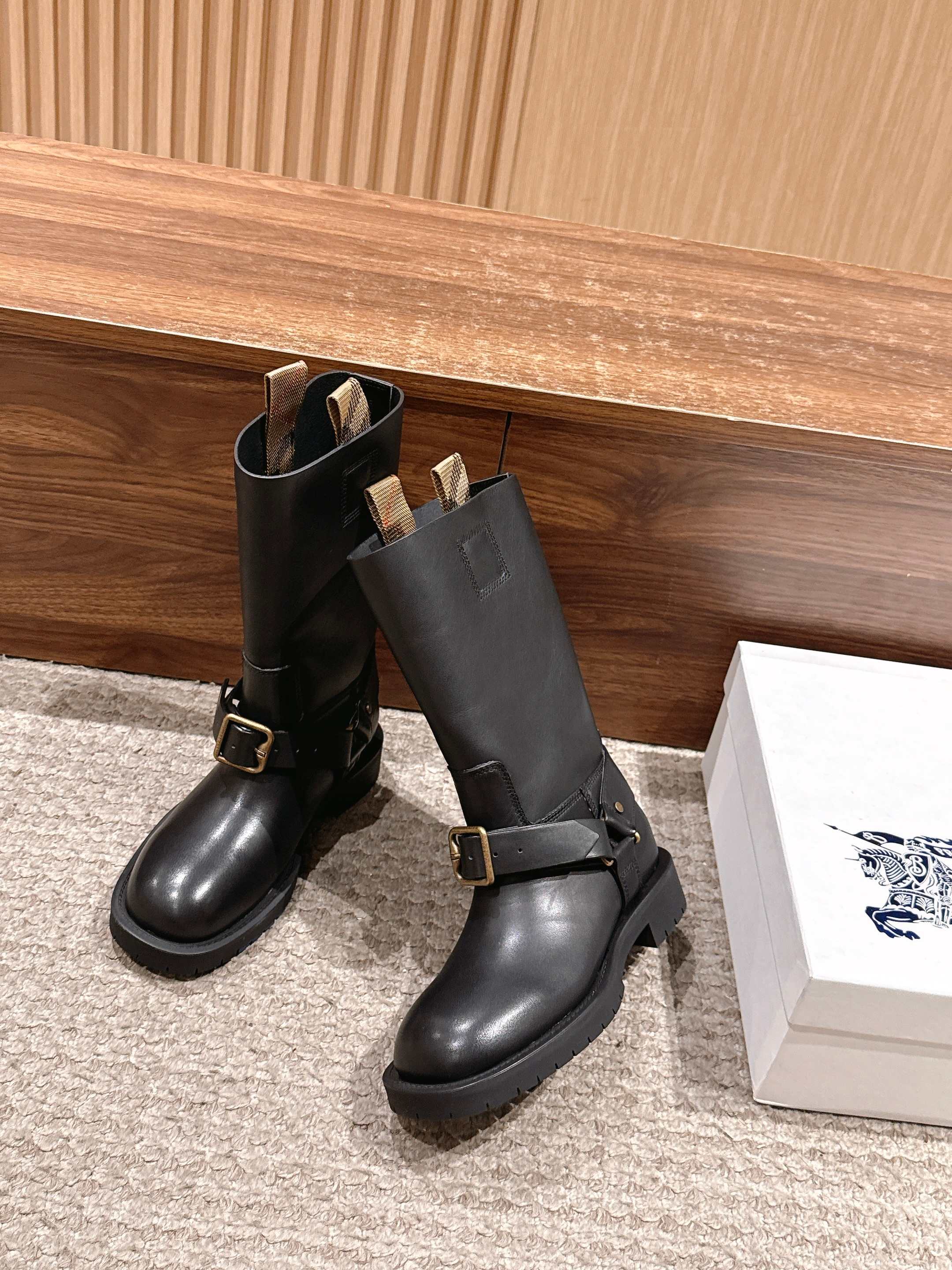 Black mid-calf leather boots with adjustable strap and gold-tone buckle detail.