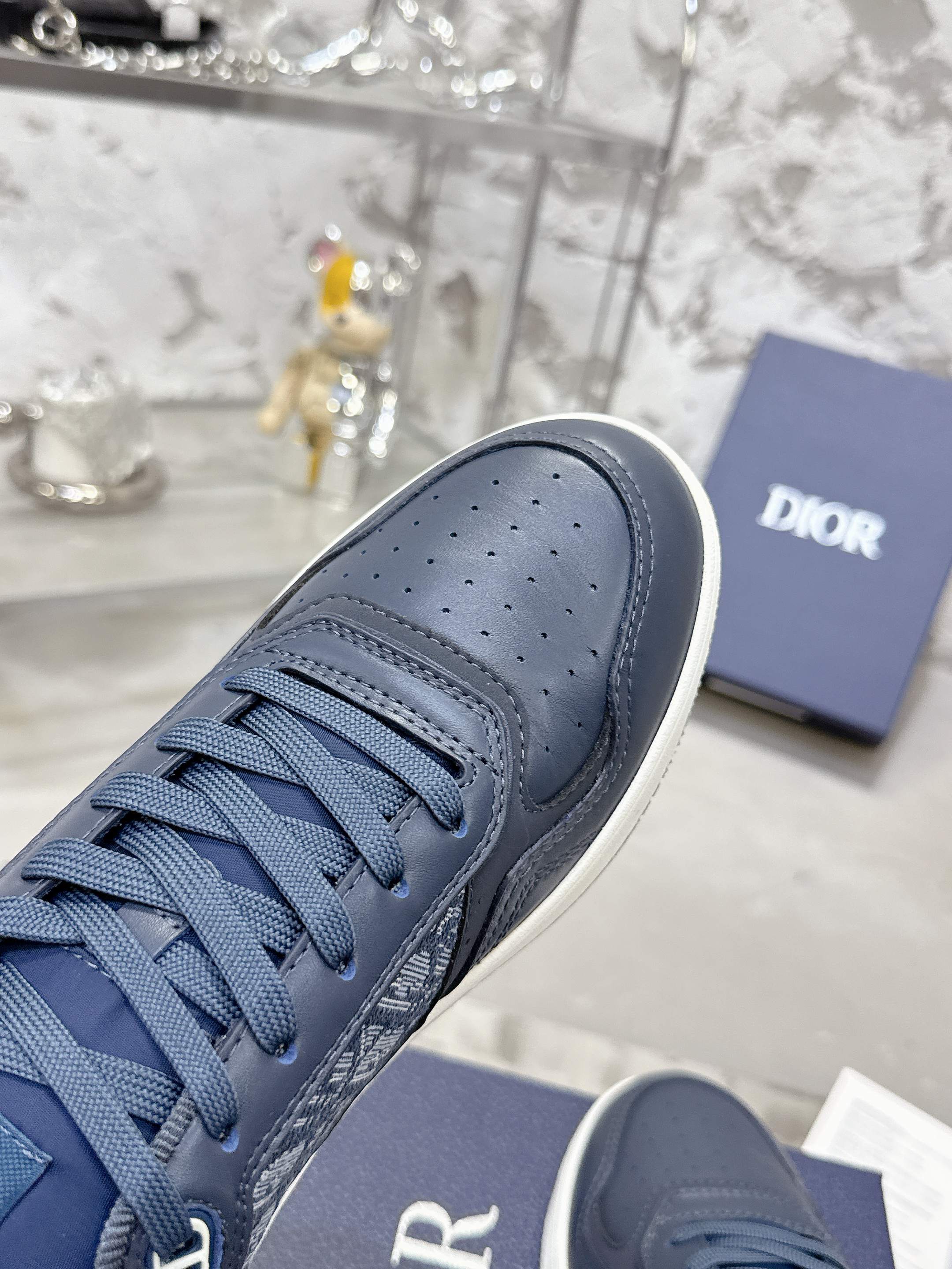 Unisex sneaker with dark blue leather upper, lace-up design, and perforated toe