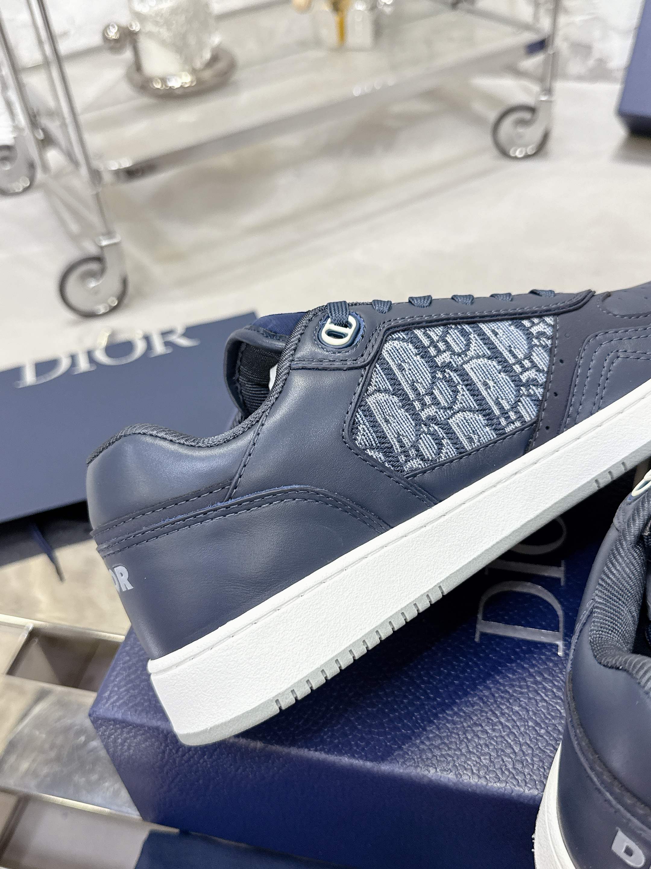 Unisex sneaker side with dark blue leather and Dior-pattern panel, white platform sole