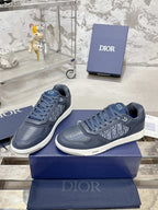 Pair of unisex low-top sneakers in dark blue with lace-up front and white soles on boxes