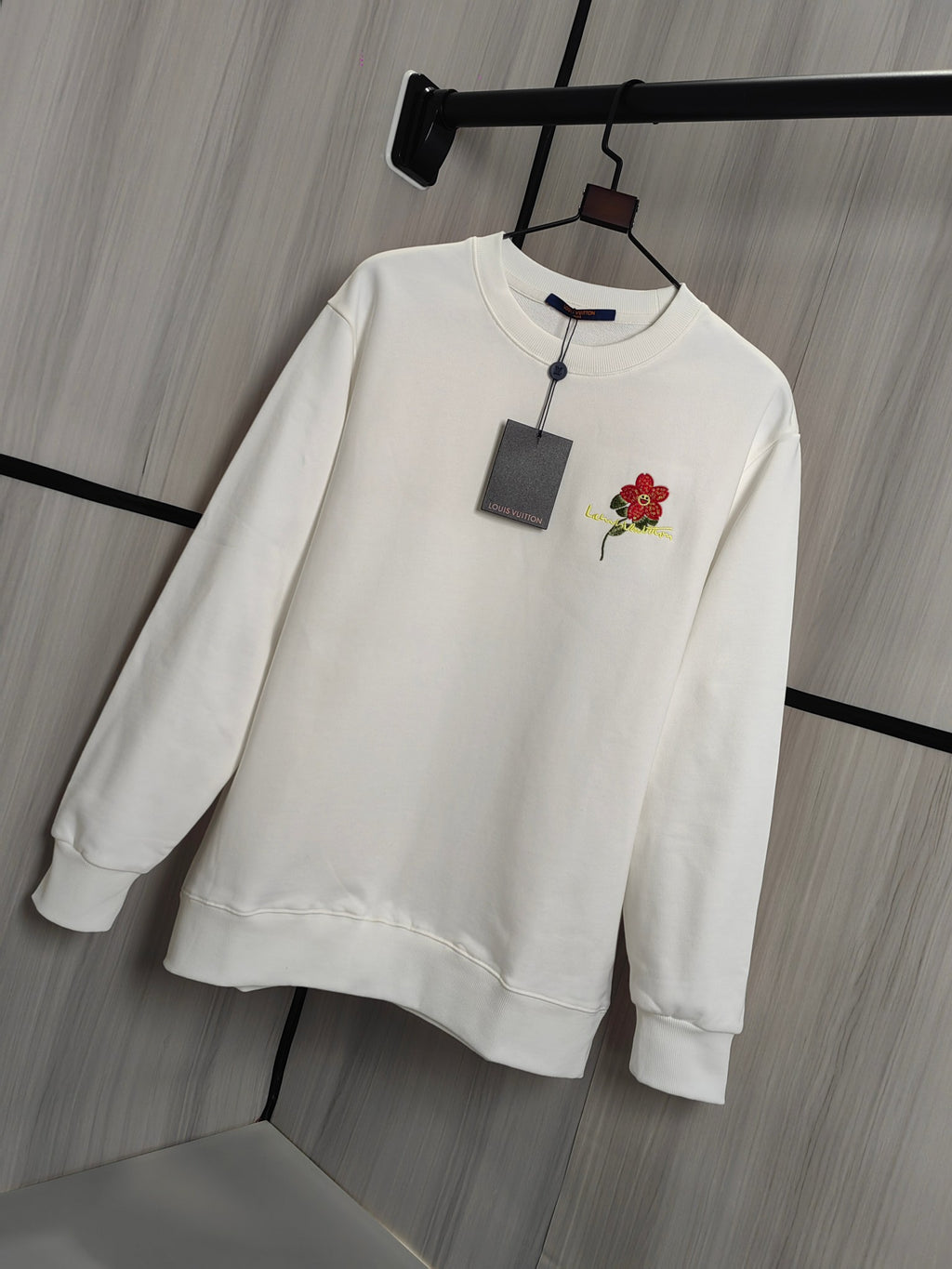 White crewneck sweatshirt on hanger with red flower chest applique
