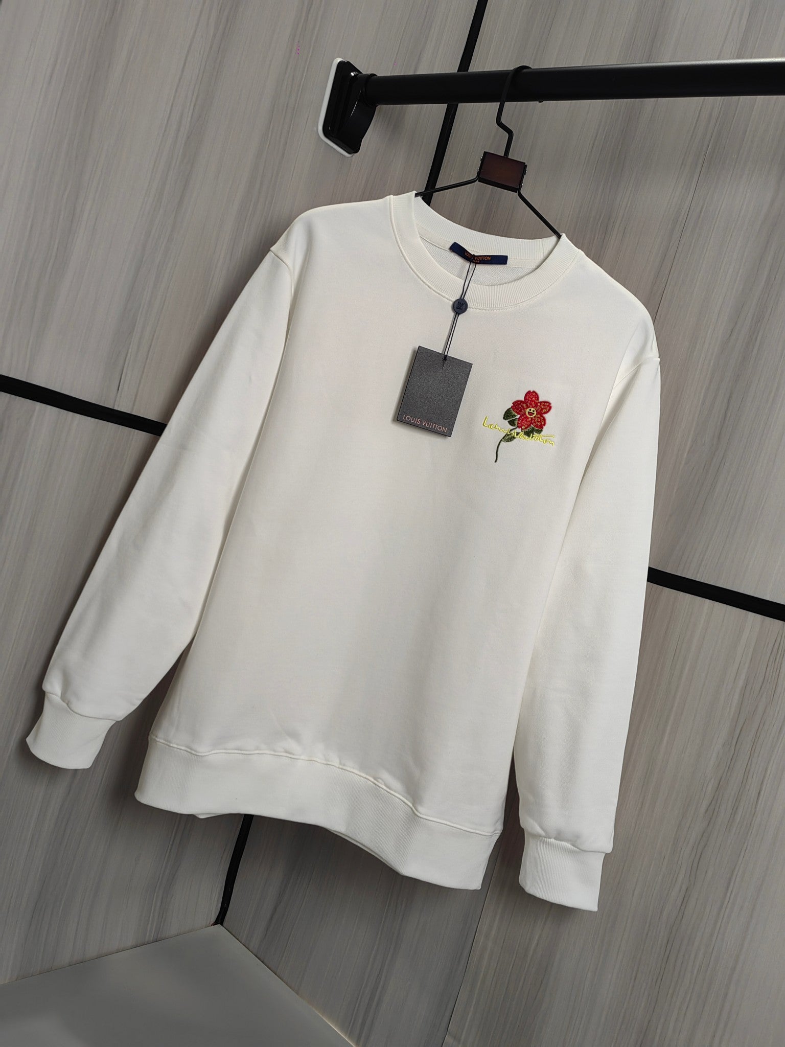 White crewneck sweatshirt on hanger with red flower chest applique