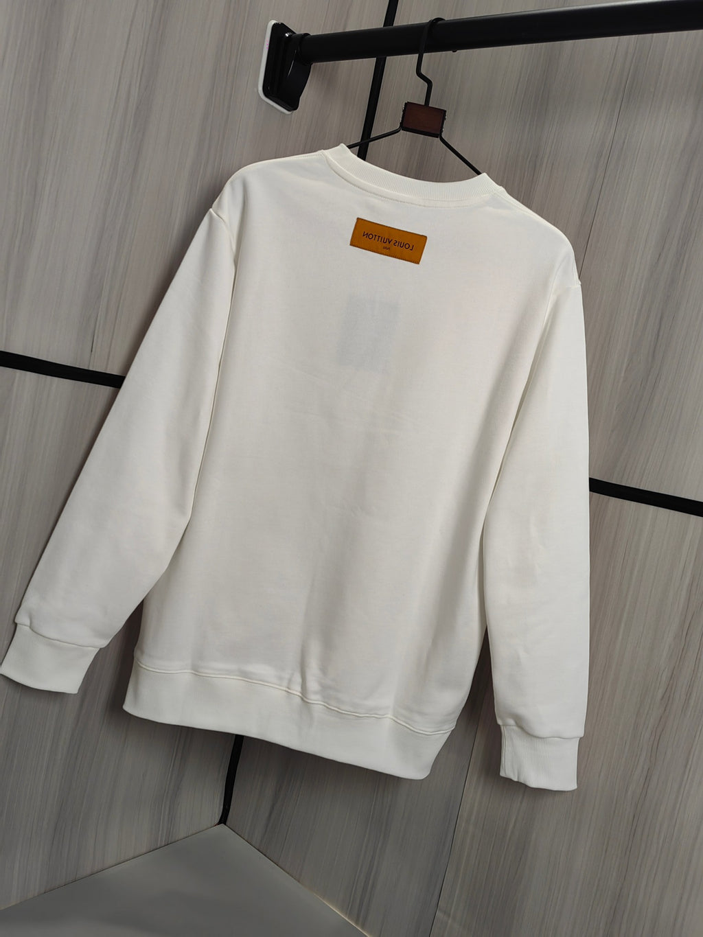 White crewneck sweatshirt back view with orange neck label on hanger
