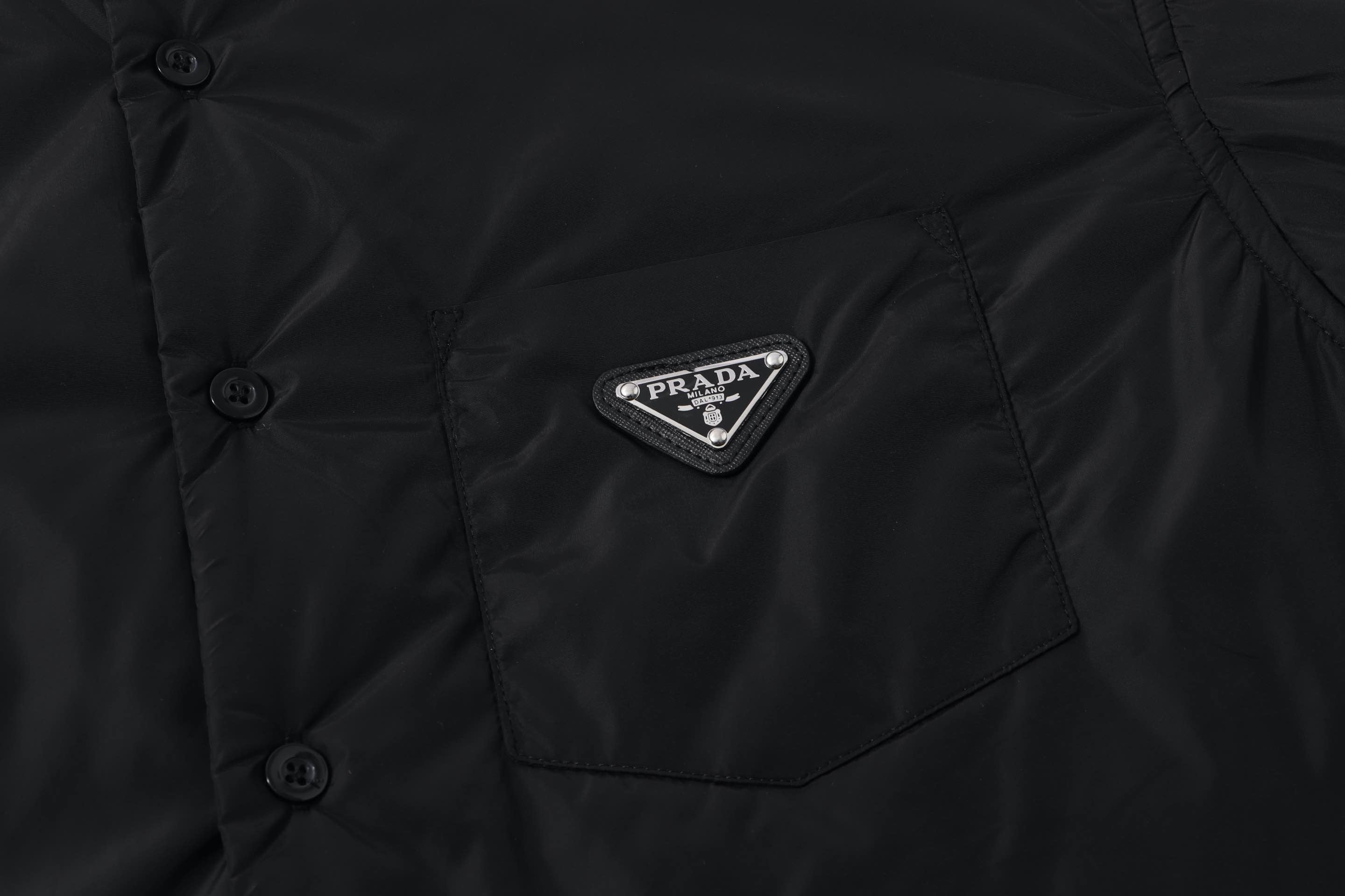 Black button-up shirt chest pocket with Prada logo patch and button details