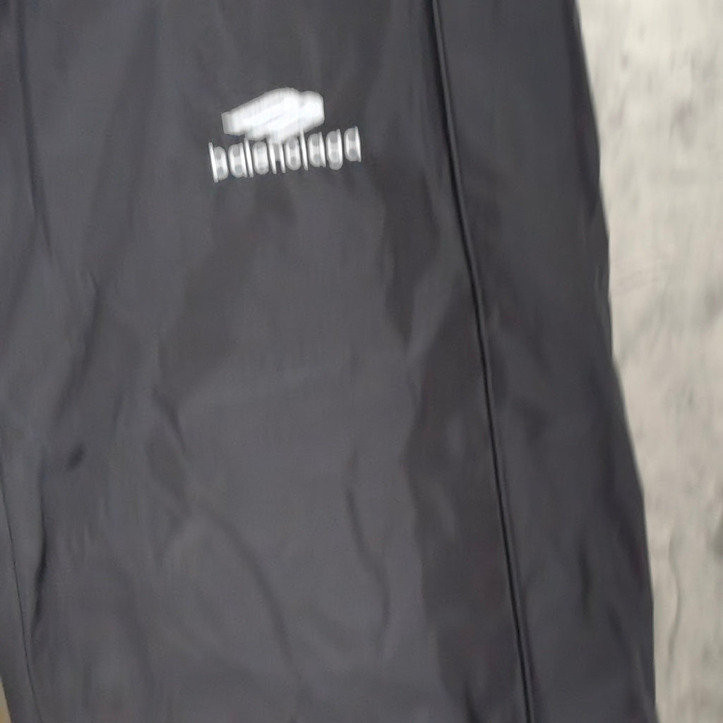 Close-up of black pants leg with Balenciaga logo print on fabric