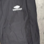 Close-up of black pants leg with Balenciaga logo print on fabric