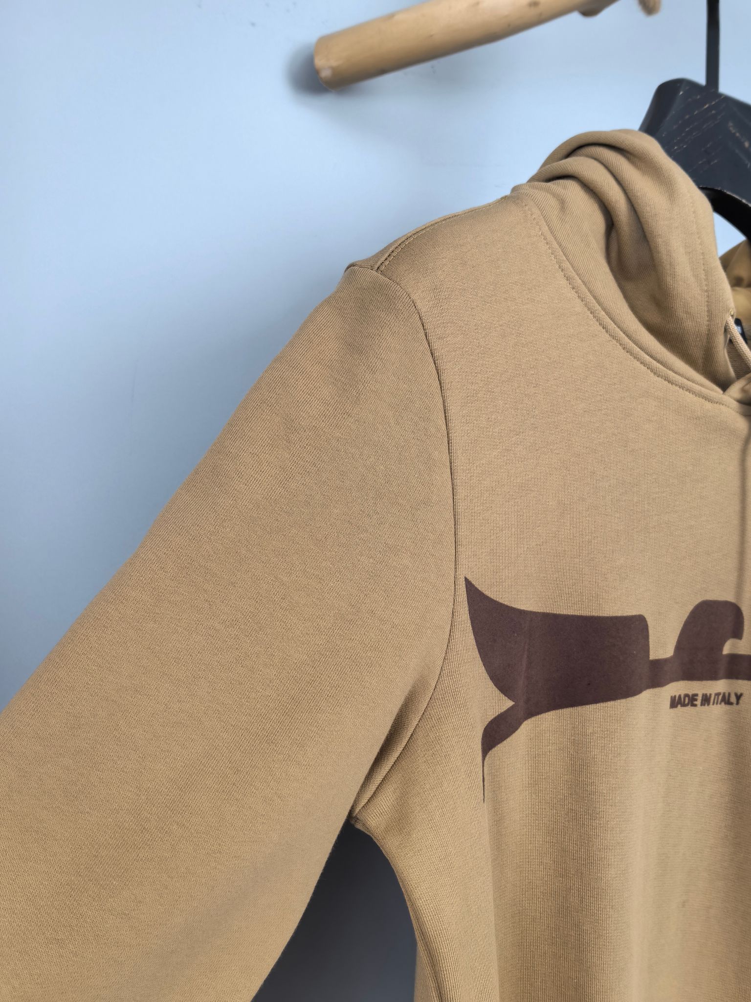 Tan hoodie sleeve and chest graphic panel, side view on hanger