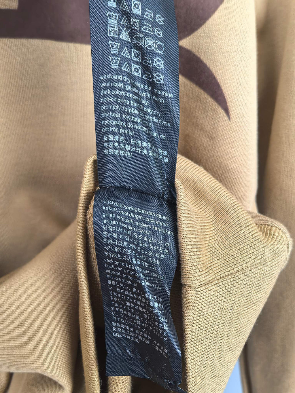 Tan hoodie interior care label tag attached near inner collar