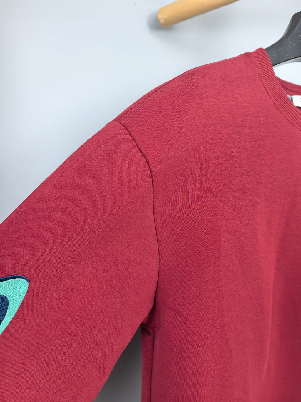 Red long-sleeve sweatshirt sleeve with partial turquoise graphic