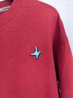 Red long-sleeve sweatshirt with small turquoise cross logo