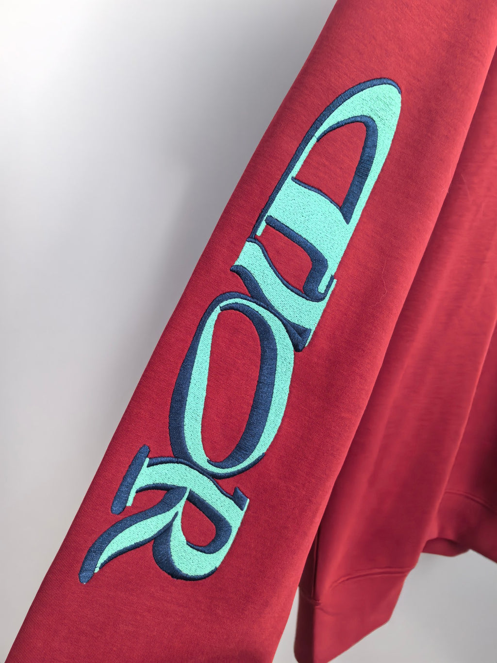 Red sweatshirt sleeve with large turquoise graphic lettering