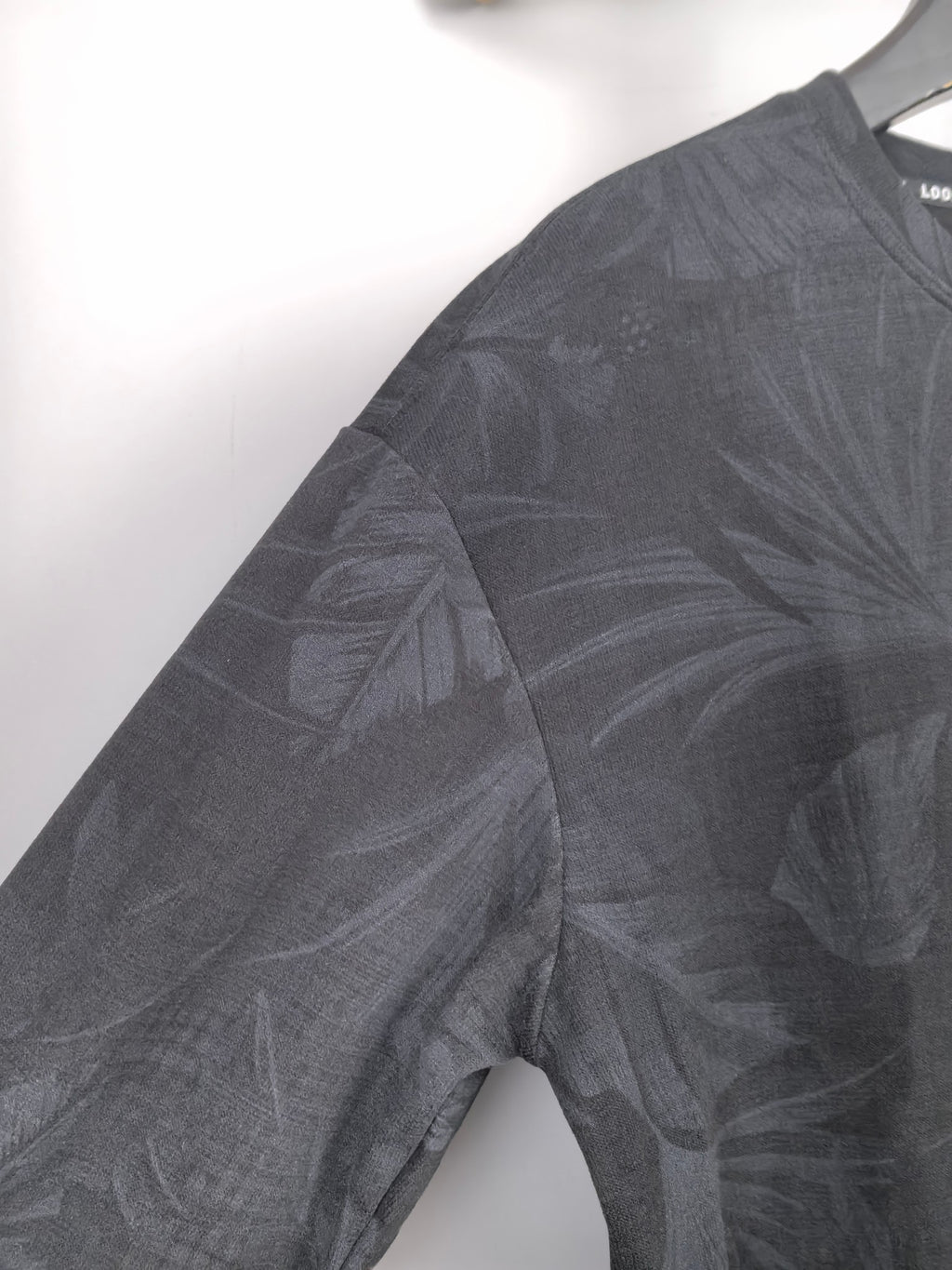 Long-sleeve sweatshirt sleeve with dark gray leaf print, crew neck edge.